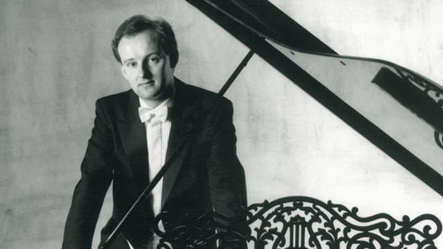 James Lisney leaning on piano