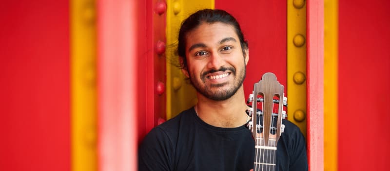Samrat Majumder with guitar on red and yellow background